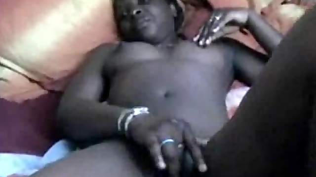Ugly Black chick lies on a bed touching her vagina