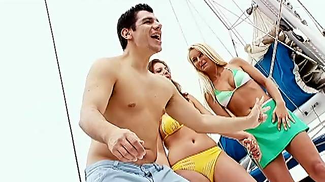 Two divine angels are making out with a guy on yacht