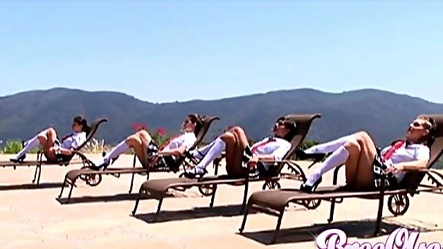 Four beautiful ladies in plaid skirts and knee high socks tan outdoors