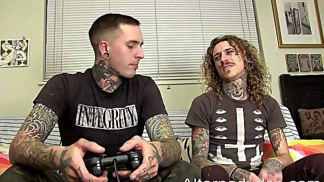 Tattooed gay guy with long dark blonde hair enjoying an awesome ass fuck