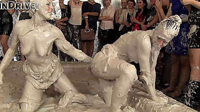 Two brunette bombshells wrestling in a pool of mud